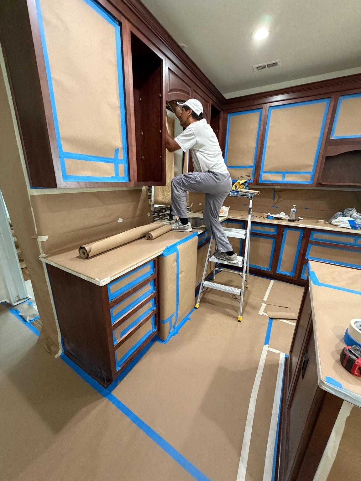 Painter working in a kitchen with surfaces masked and protected